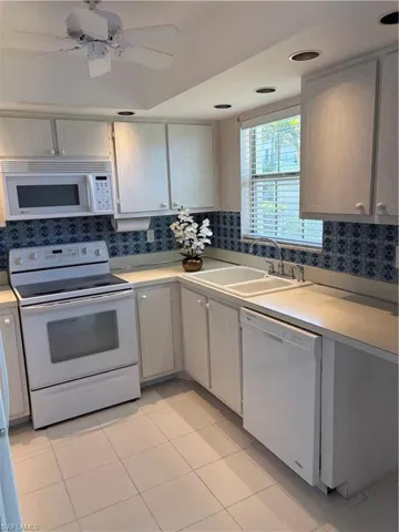 Kitchen featuring white appliances, light countertops, a ceiling fan, light tile patterned floors, and white cabinets