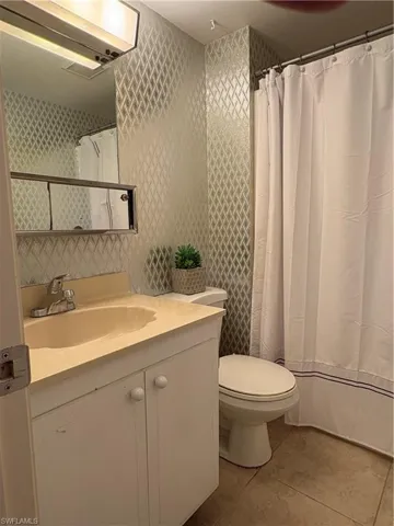 Full bathroom with vanity, a shower with shower curtain, and light tile patterned floors