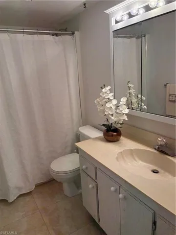Full bath featuring vanity, curtained shower, and light tile patterned floors