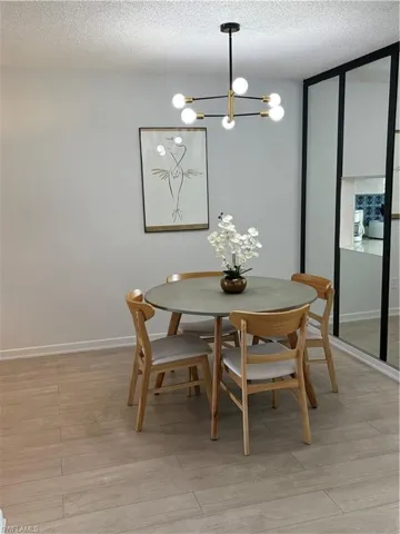Dining room with light wood finished floors, a textured ceiling, and a chandelier