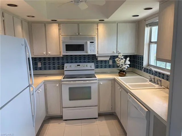 Kitchen featuring white appliances, light countertops, light tile patterned floors, and ceiling fan