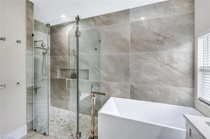 Bathroom featuring a freestanding bath, a stall shower, and vanity