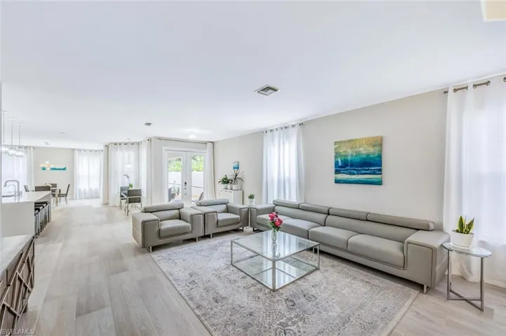 Living room with light wood finished floors, french doors, and healthy amount of natural light