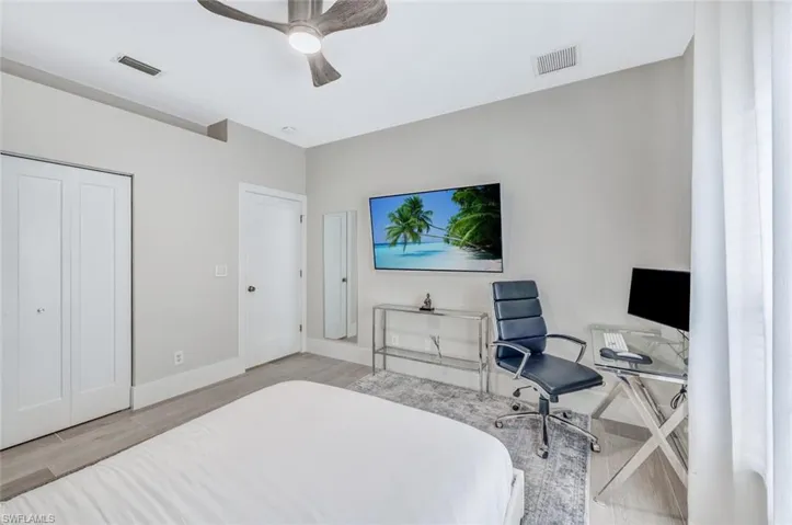 Bedroom featuring light wood-style floors, a desk, ceiling fan, and a closet