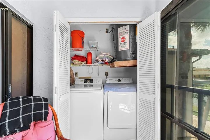 Laundry area with a textured wall, electric water heater, and washing machine and dryer