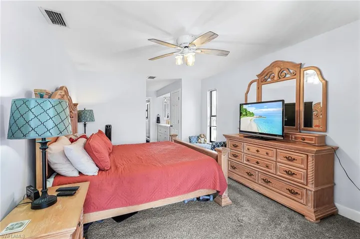 Carpeted bedroom featuring connected bathroom and ceiling fan