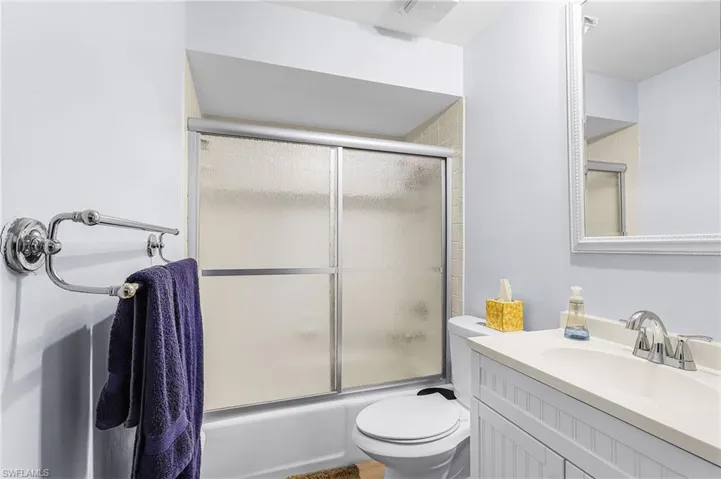 Bathroom featuring vanity and shower / bath combination with glass door