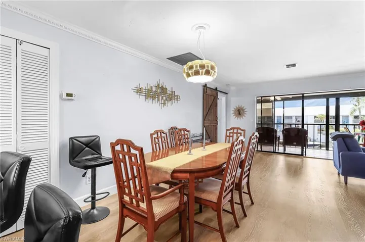 Dining room featuring a barn door, ornamental molding, and light wood-style flooring