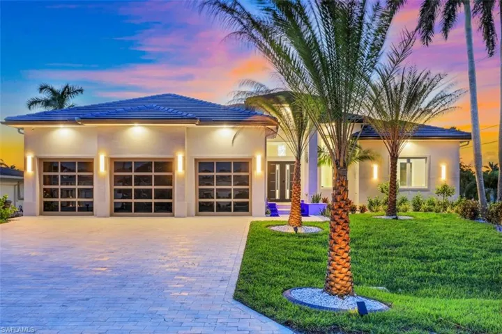 View of front of house with decorative driveway, a garage, a yard, stucco siding, and a tiled roof