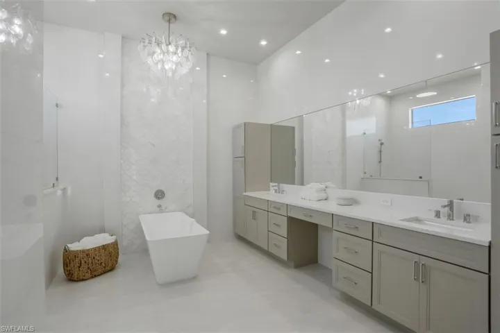Bathroom with double vanity, a soaking tub, and a chandelier