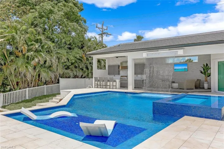 View of swimming pool with an outdoor bar, a fenced backyard, a patio area, and a pool with connected hot tub