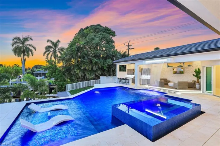 Pool at dusk featuring an outdoor living space, a patio, and a pool with connected hot tub