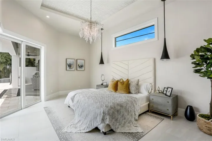 Bedroom with access to outside, a chandelier, baseboards, and a towering ceiling