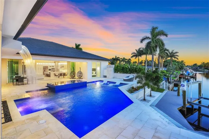 View of pool featuring a patio, boat lift, a boat dock, and a pool with connected hot tub
