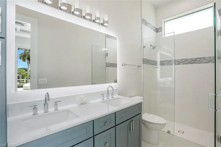 Bathroom with a stall shower, double vanity, toilet, and tile patterned floors