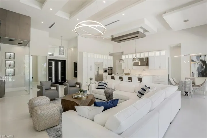 Living area with a high ceiling, beam ceiling, a chandelier, and recessed lighting