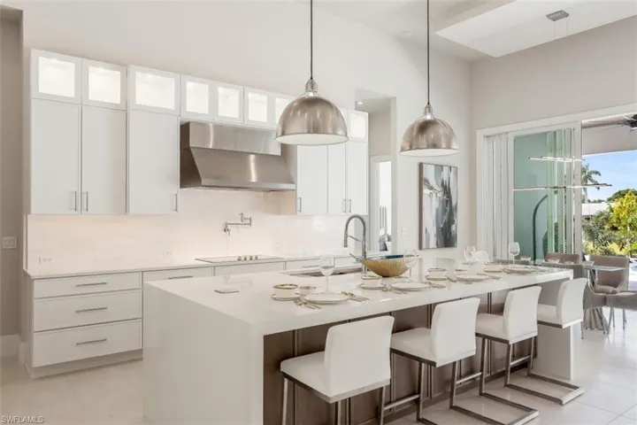 Kitchen with wall chimney exhaust hood, tasteful backsplash, light tile patterned floors, and light countertops