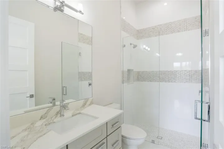 Full bathroom featuring a stall shower, toilet, and vanity