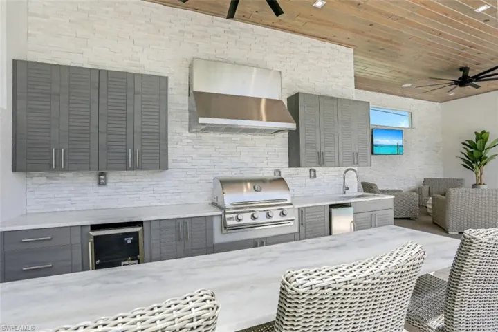 View of patio / terrace featuring ceiling fan, a sink, beverage cooler, and outdoor dining area