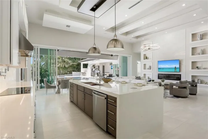 Kitchen with a sink, stainless steel dishwasher, built in features, light countertops, and a large island with sink