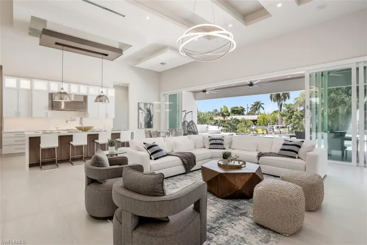 Living area with a towering ceiling, a ceiling fan, light tile patterned floors, and beamed ceiling