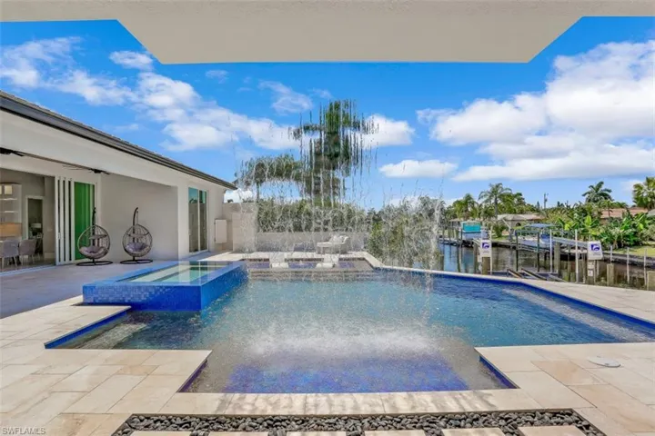 View of pool with a pool with connected hot tub, a patio, and a water view