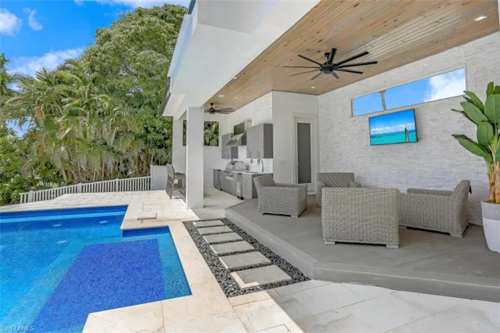 Swimming pool with an outdoor kitchen, ceiling fan, and a patio