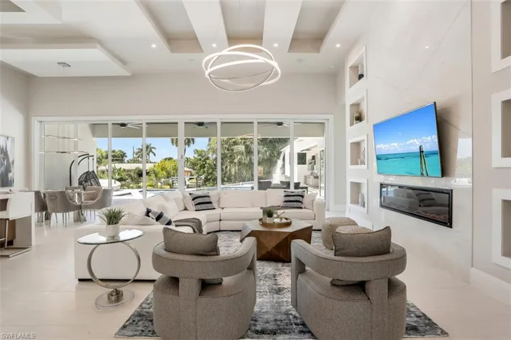 Living room with healthy amount of natural light, a premium fireplace, a high ceiling, a sunroom, and recessed lighting