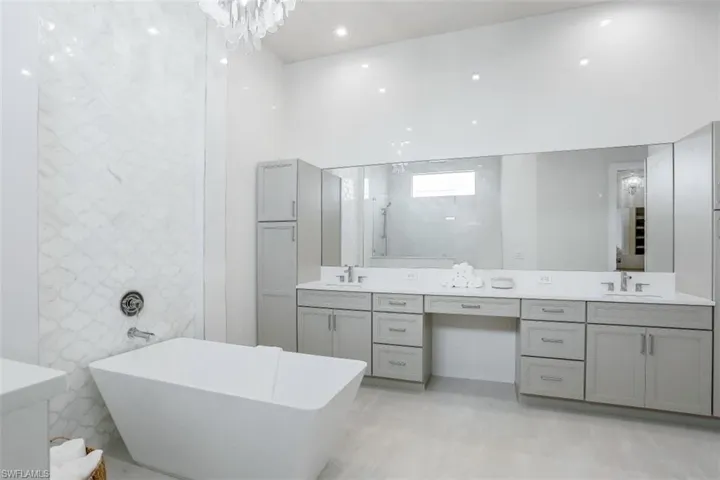 Full bathroom featuring double vanity, a freestanding tub, and a shower