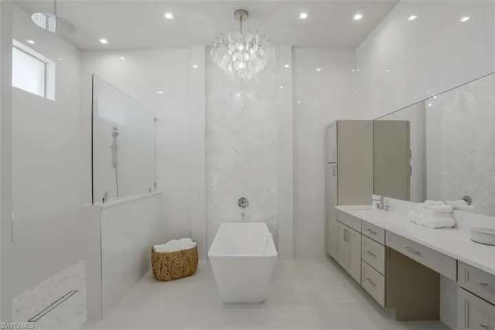 Bathroom with a freestanding bath, vanity, walk in shower, and tile patterned flooring