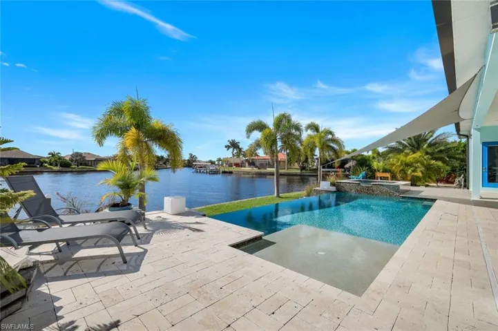 View of swimming pool featuring a patio area, a water view, and a pool with connected hot tub
