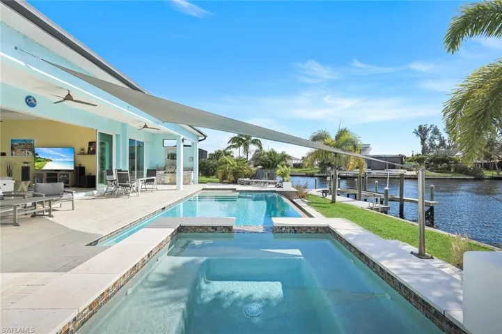 View of pool featuring boat lift, a pool with connected hot tub, a water view, a dock, and a patio area