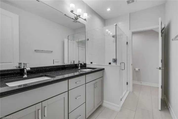 Full bathroom featuring a stall shower, double vanity, and light tile patterned flooring