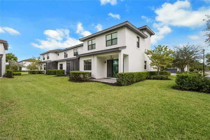 Back of property with stucco siding and a lawn