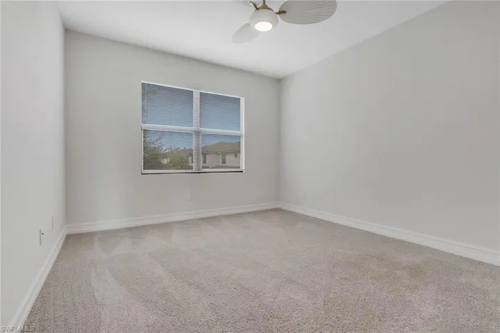 Carpeted spare room with baseboards and ceiling fan