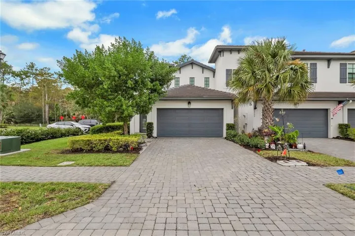 View of front facade featuring decorative driveway, a garage, stucco siding, a tiled roof, and a front yard