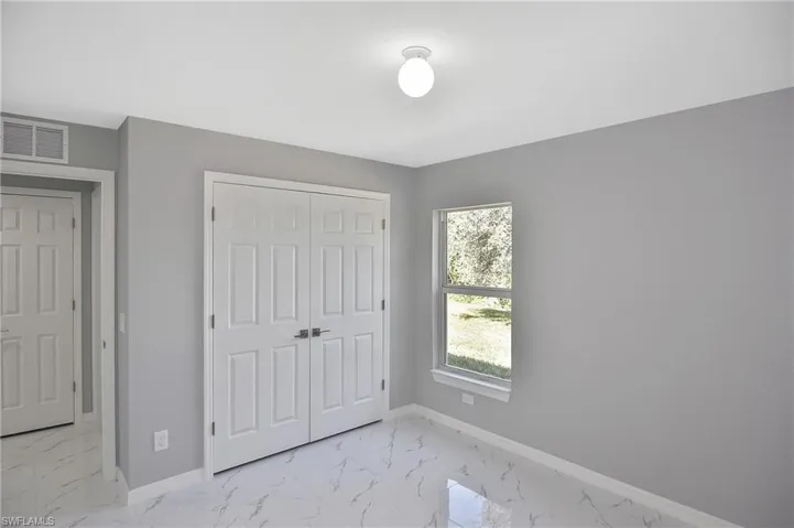 Unfurnished bedroom featuring light marble finish floors and a closet