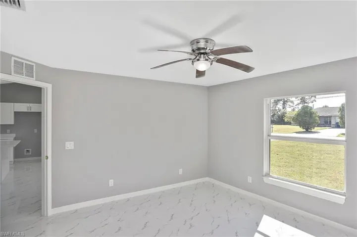 Unfurnished room with light marble finish floors and ceiling fan