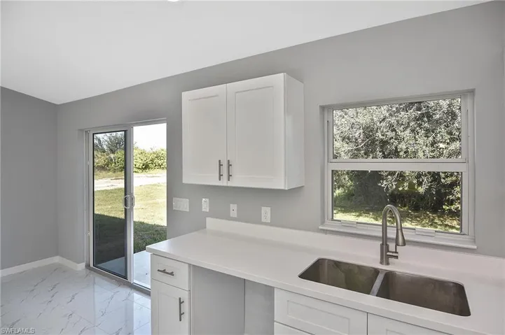 Kitchen with light marble finish flooring, white cabinets, plenty of natural light, and light stone countertops