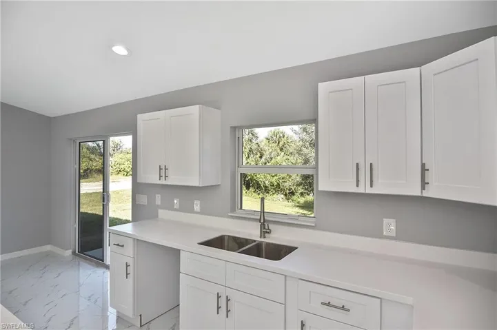 Kitchen with white cabinetry, light marble finish flooring, recessed lighting, and light stone counters
