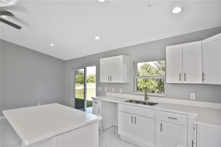 Kitchen featuring white cabinetry, light marble finish flooring, recessed lighting, and a center island