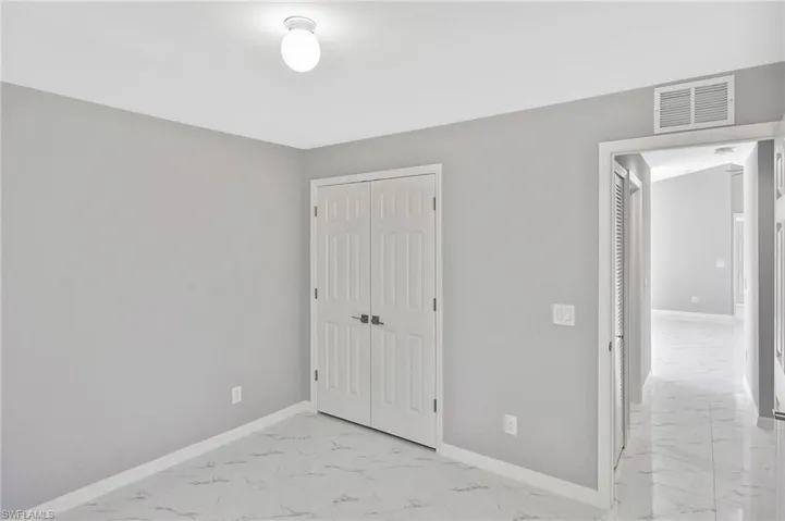 Unfurnished bedroom featuring light marble finish floors and a closet