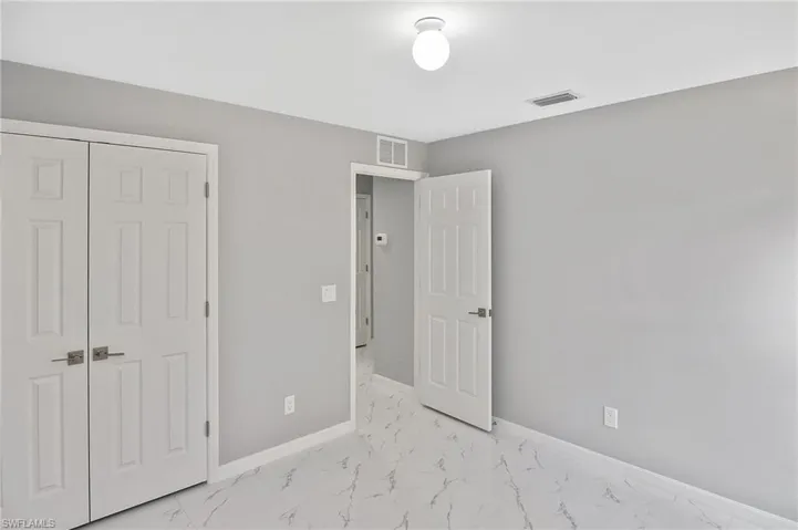 Unfurnished bedroom with light marble finish floors and a closet