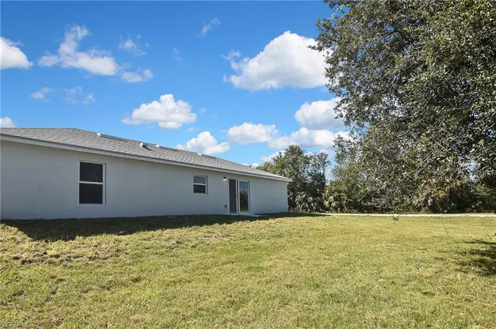 Rear view of property with a yard and stucco siding