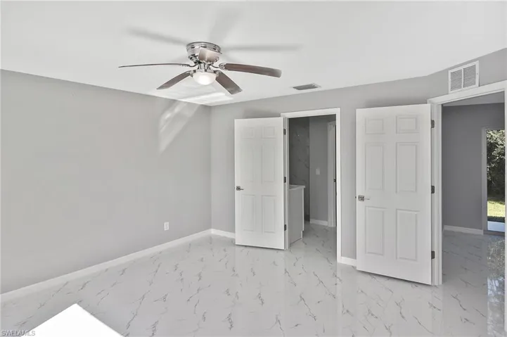 Unfurnished bedroom with light marble finish floors and a ceiling fan
