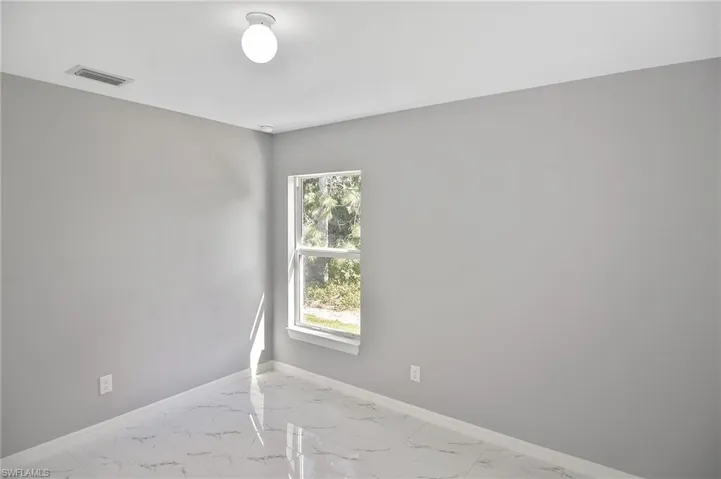 Unfurnished room with light marble finish floors and baseboards