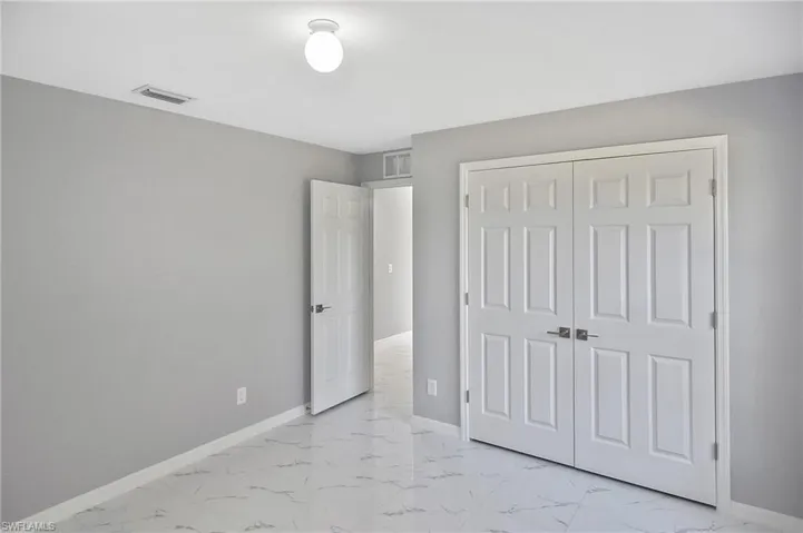 Unfurnished bedroom with light marble finish floors and a closet
