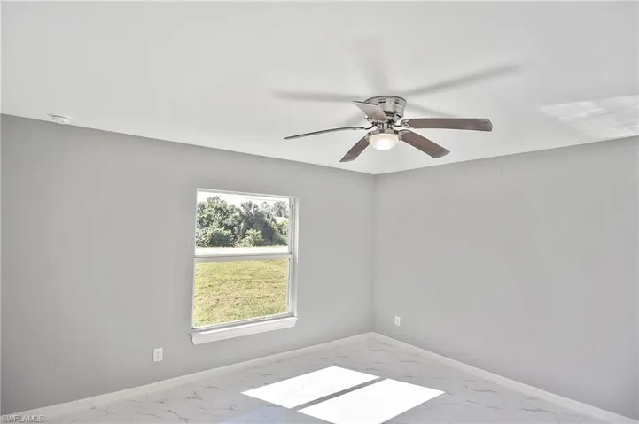 Unfurnished room featuring marble look tile flooring and a ceiling fan