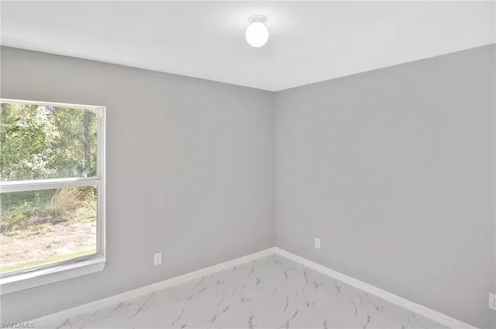 Spare room featuring baseboards and marble finish floors