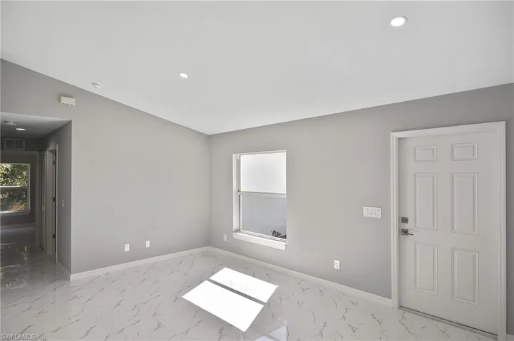 Unfurnished room featuring light marble finish flooring, recessed lighting, and lofted ceiling